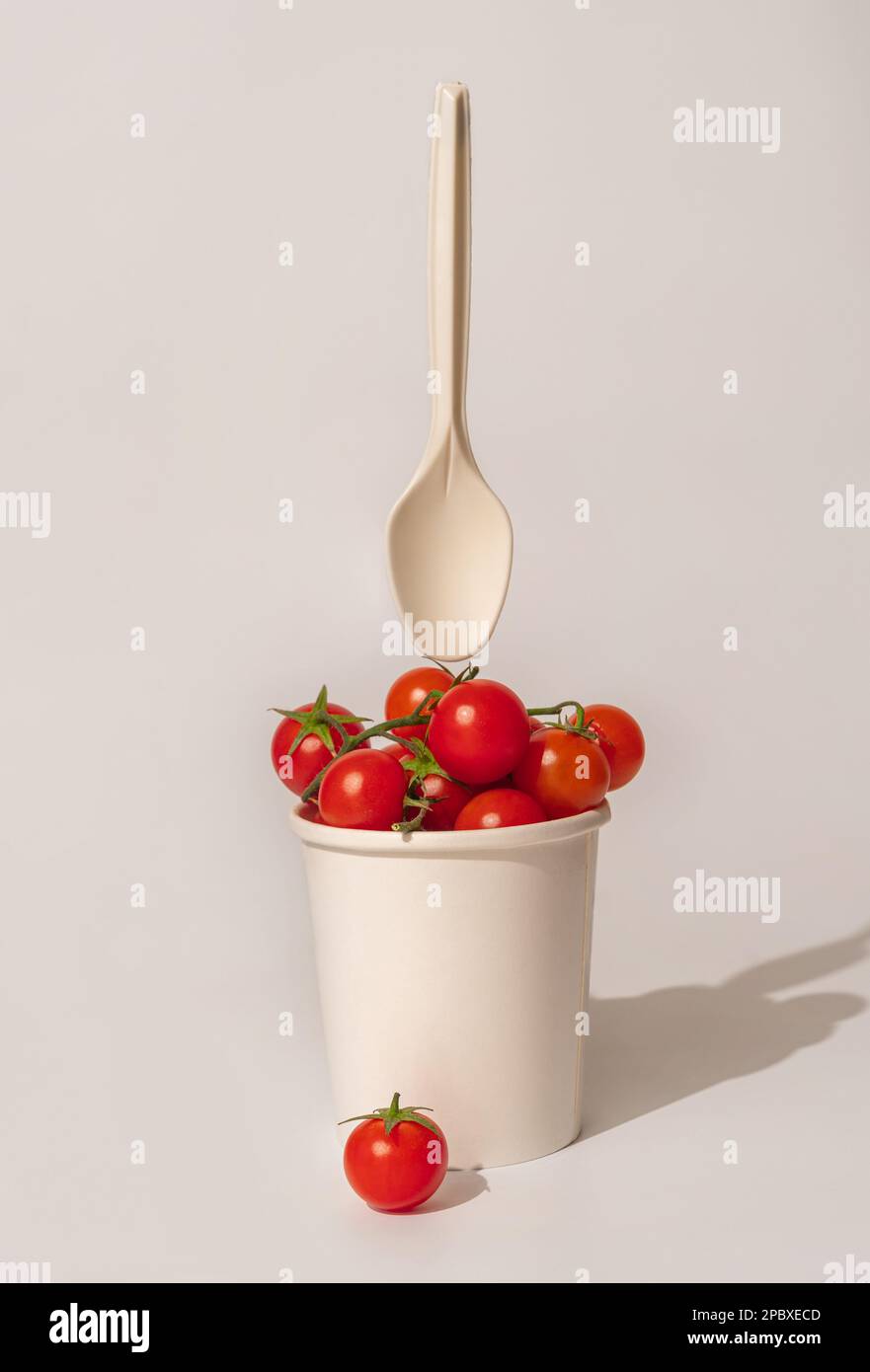 Fresh cherry tomatoes in a paper cup on light background. Stock Photo