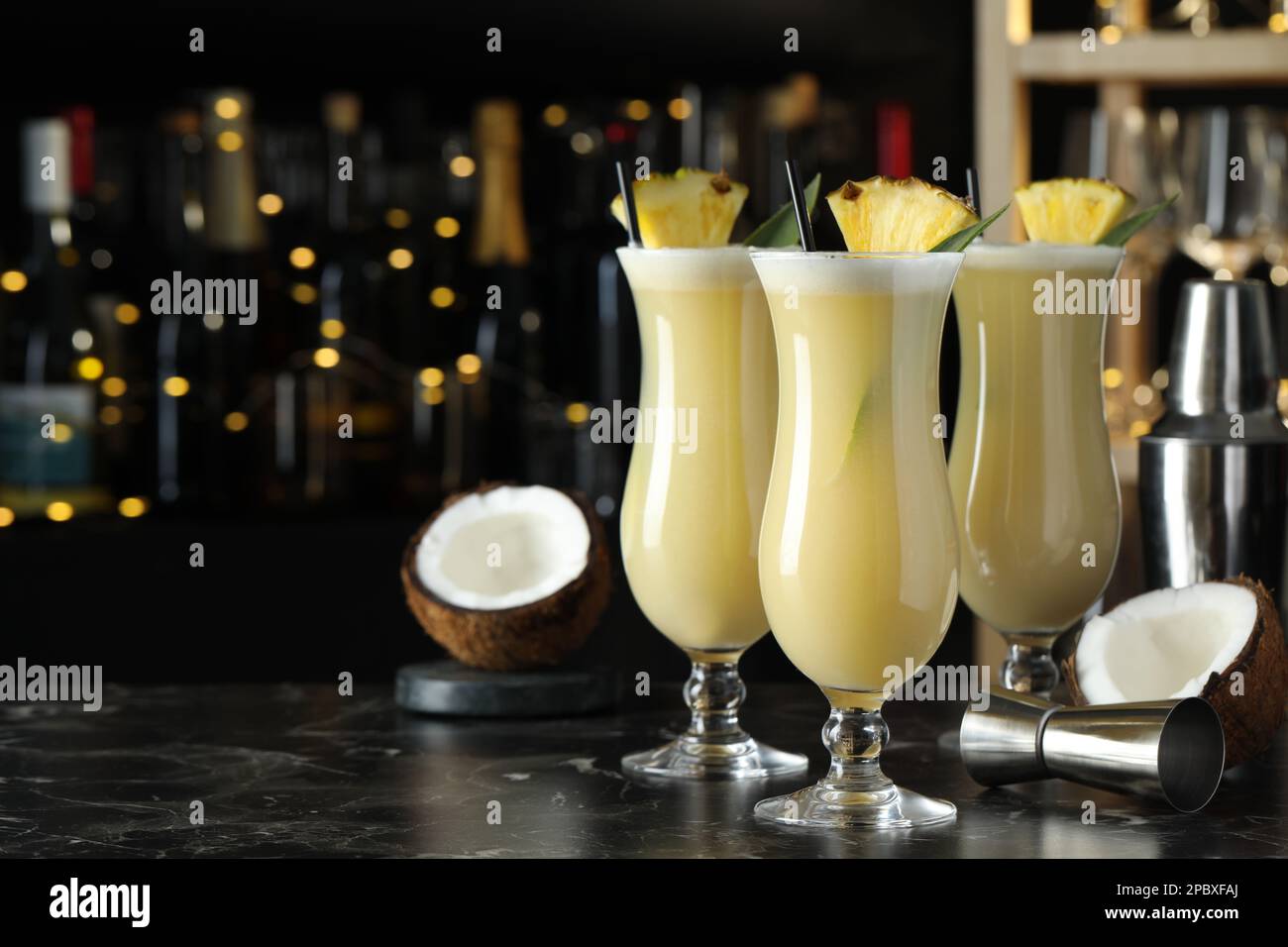 Tasty Pina Colada cocktails on black marble bar countertop, space for text Stock Photo