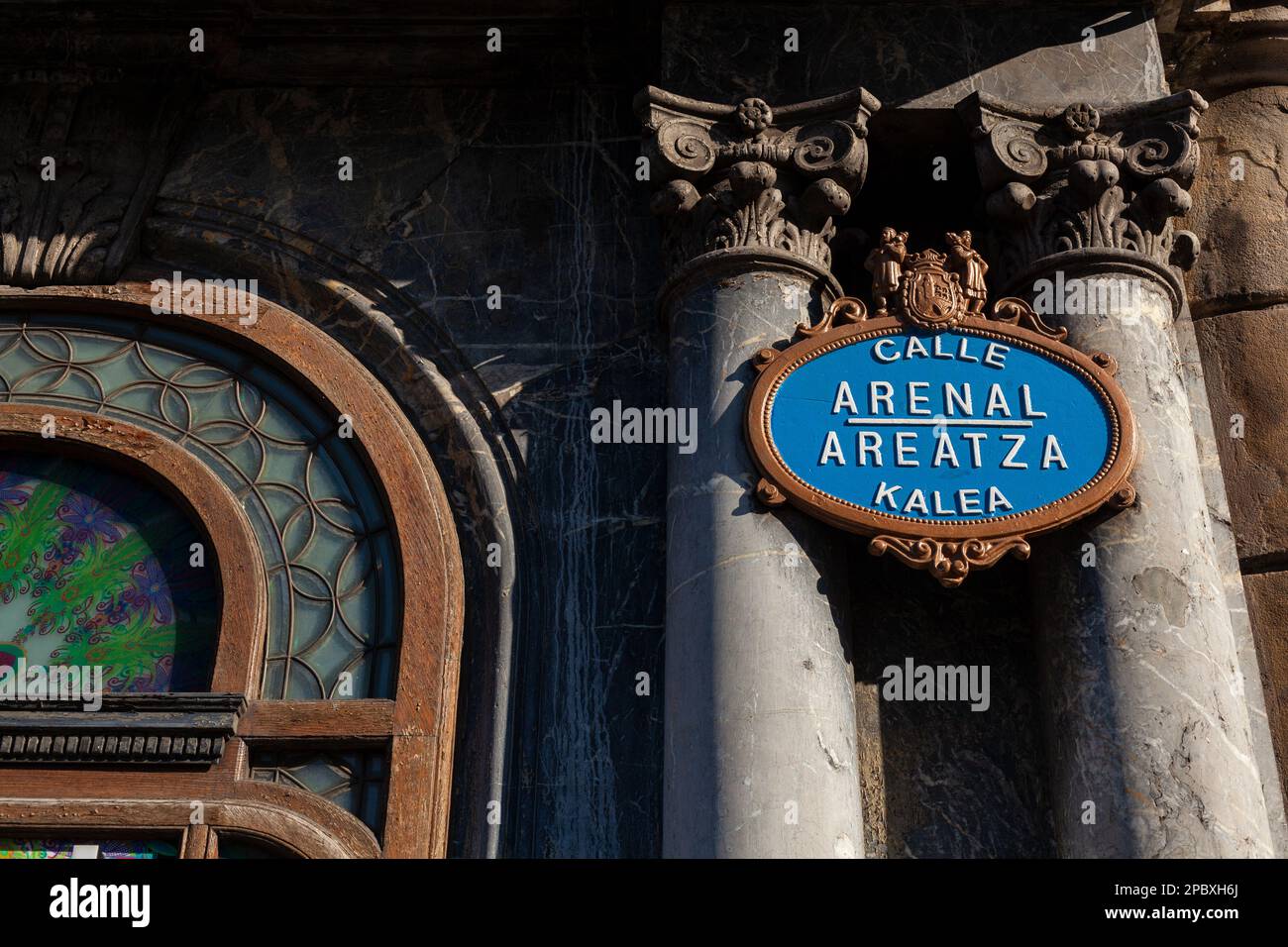 Ornate gold and blue street name plaque on the corner of Arenal Areatza