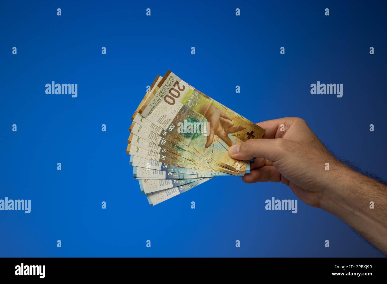 a-spread-mix-of-200-and-100-swiss-francs-banknotes-held-in-hand-by-a