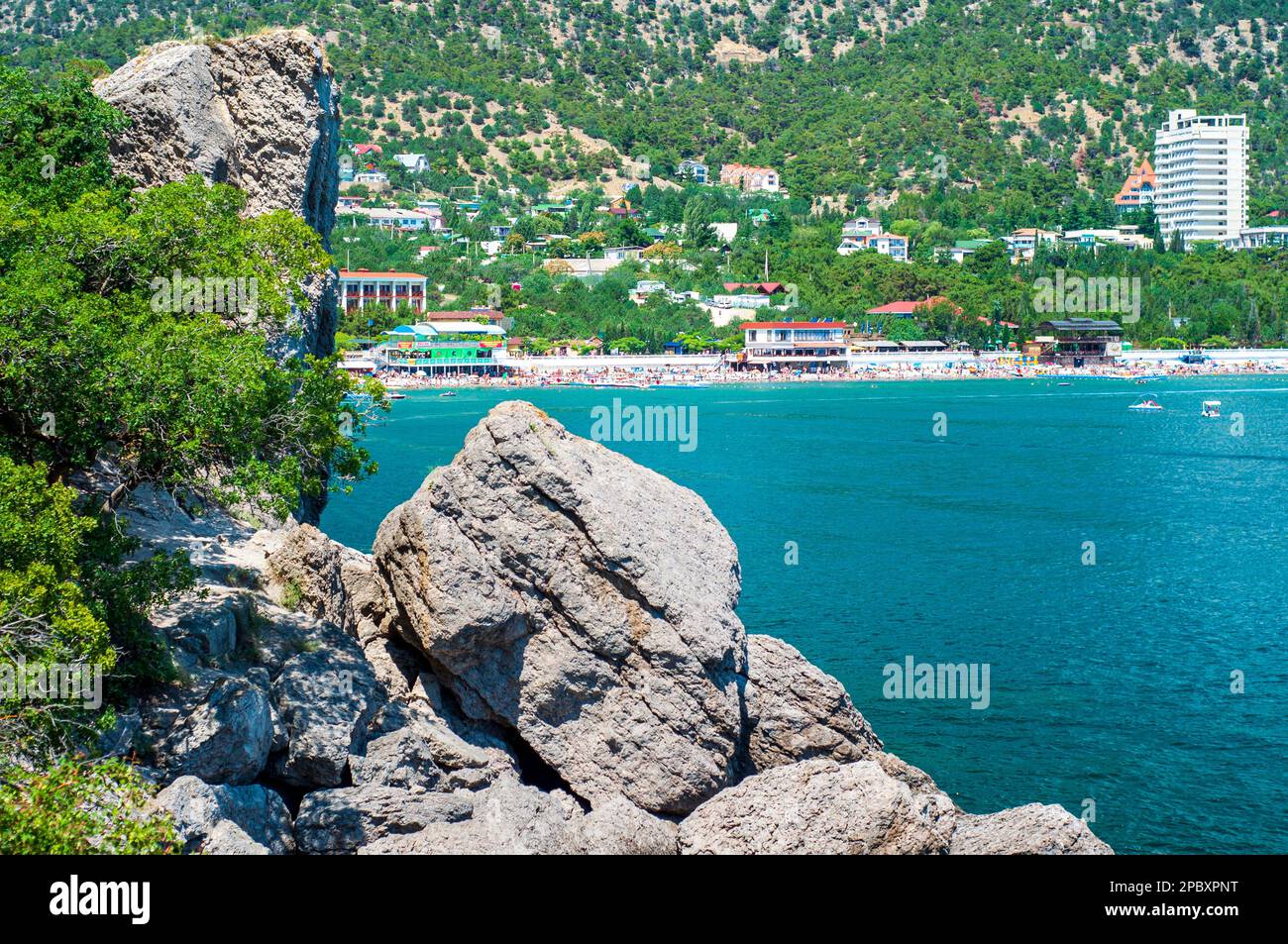 A rocky shore above the sea and a resort town with a beach in the background. Rest in Crimea, Ukraine Stock Photo