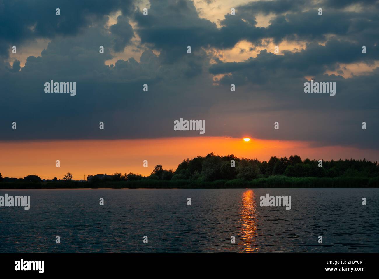 Sunset with dark clouds over the calm lake Stock Photo