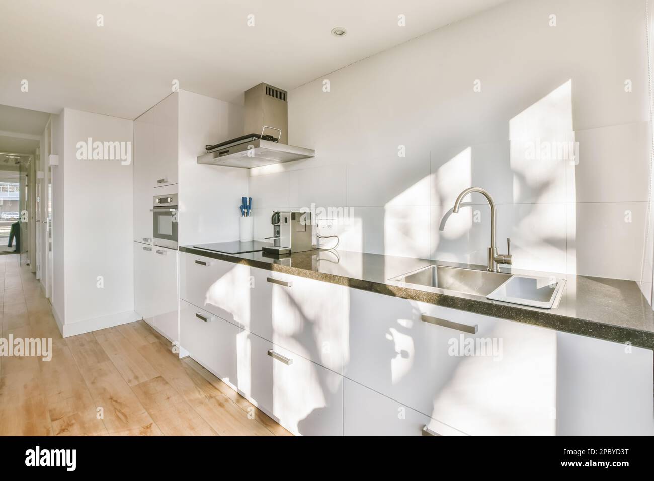 Interior of stylish open plan kitchen with white cabinets and built in ...