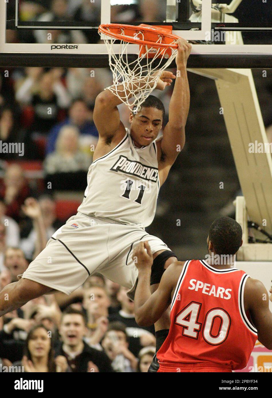 Providence's Geoffrey McDermott (11) hangs on the rim following a slam dunk  as St. John's Aaron Spears (40) looks on during a basketball game Saturday,  Feb. 17, 2007, in Providence, R.I. Providence