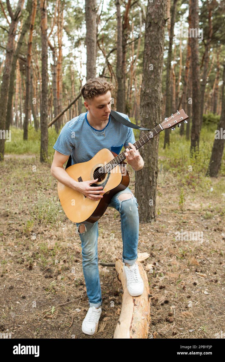 Pensive man playing guitar forest concept. Stock Photo
