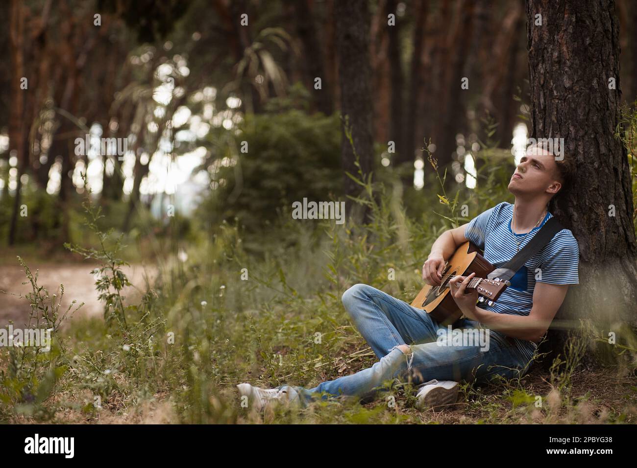 Pensive man playing guitar forest concept. Stock Photo