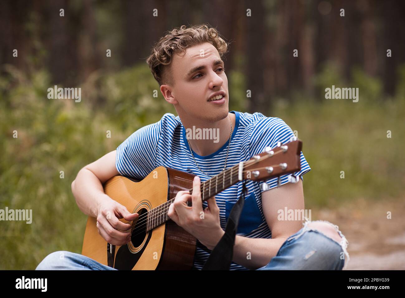 Smiling man playing guitar forest concept. Stock Photo