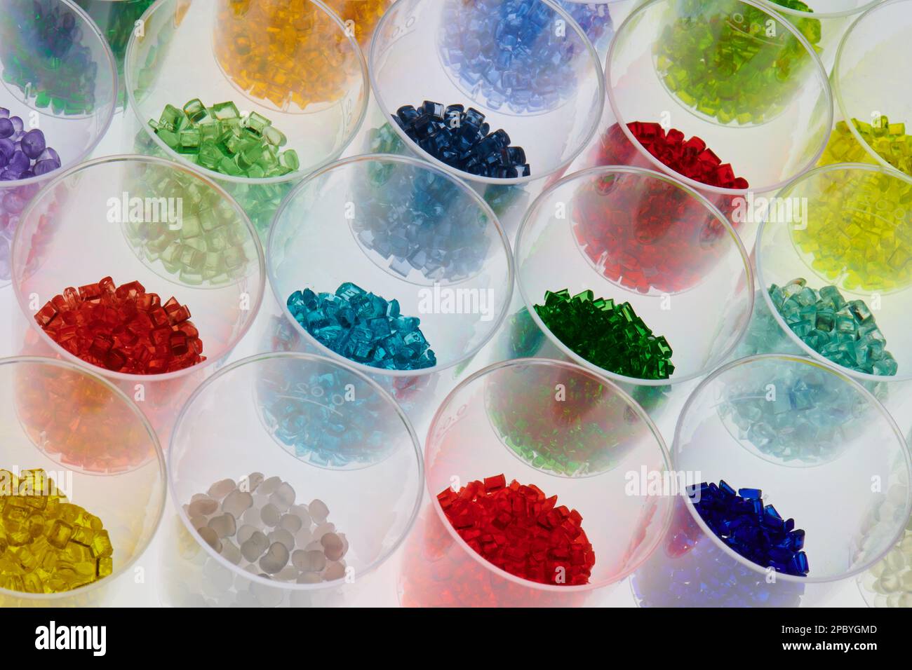 several transparent colored plastic resin granulates in test glasses in laboratory. Mass for injection molding and extrusion process Stock Photo