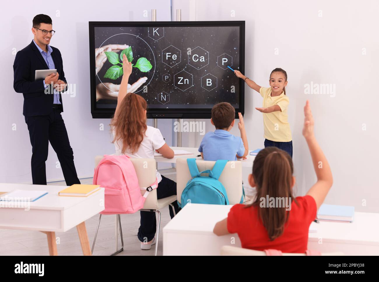 Teacher and pupil using interactive board in classroom during lesson Stock Photo