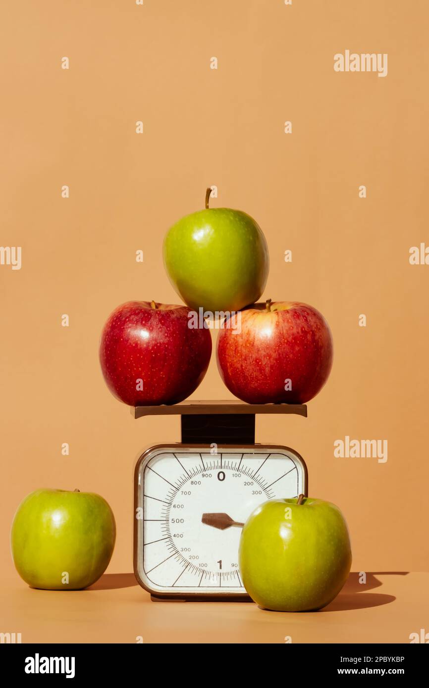 Fresh and juicy red and green apples on weighing scale as part of healthy calorie controlled diet on colored background Stock Photo