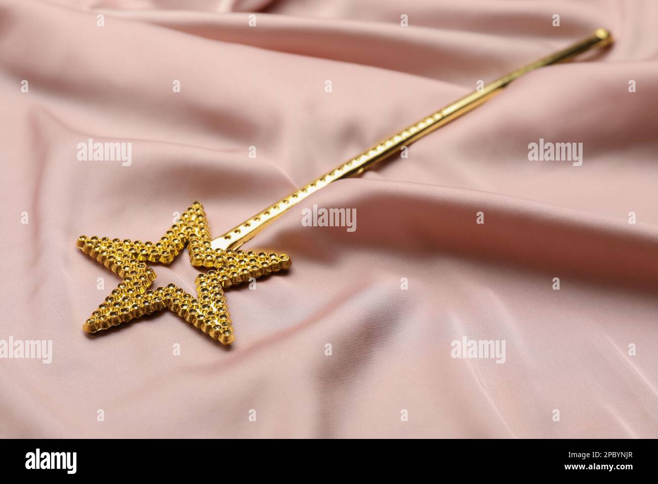 Beautiful golden magic wand on pink fabric Stock Photo