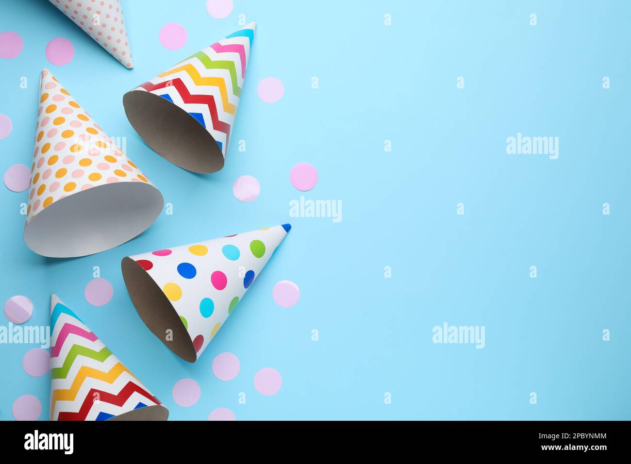 Bright party hats and confetti on light blue background, flat lay ...