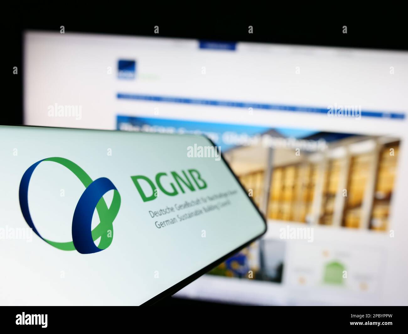 Smartphone with logo of Deutsche Gesellschaft für Nachhaltiges Bauen (DGNB) on screen in front of website. Focus on left of phone display. Stock Photo