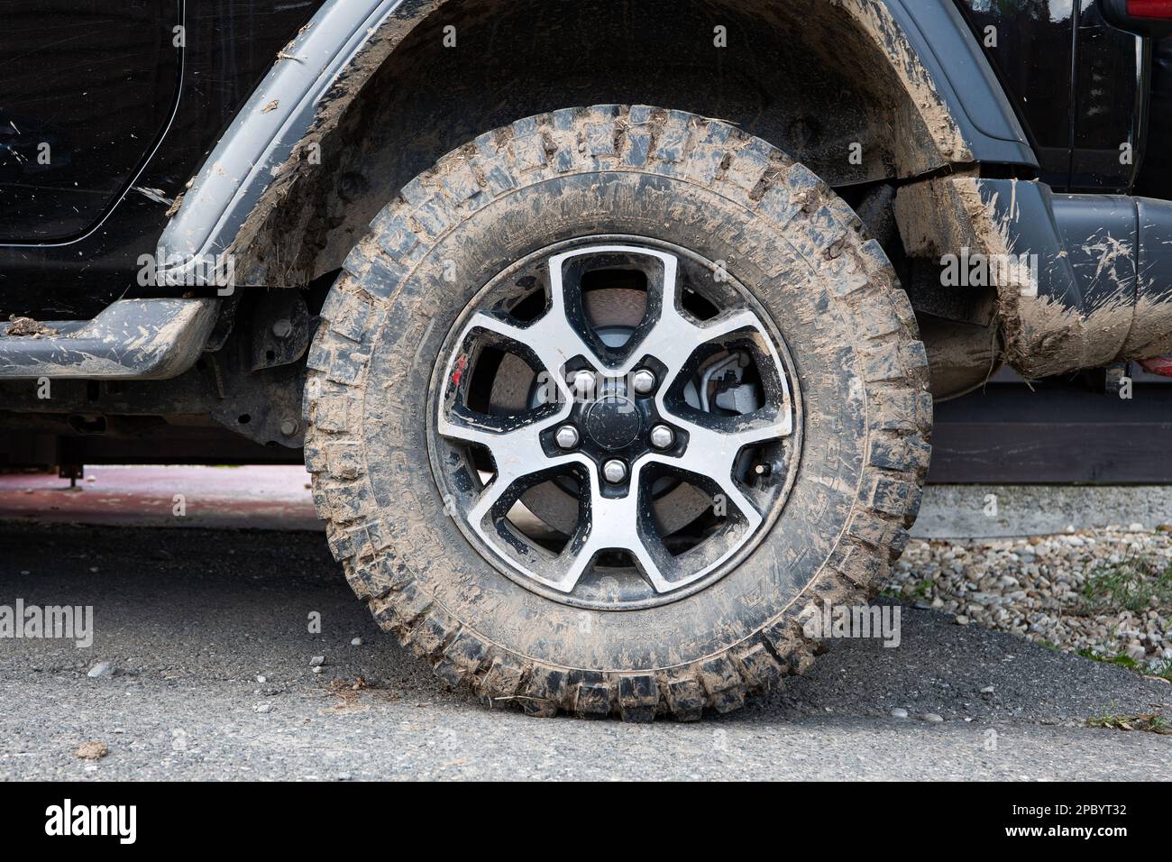 Dried mud on SUV's offroad mud tires. Close up low angle view, no