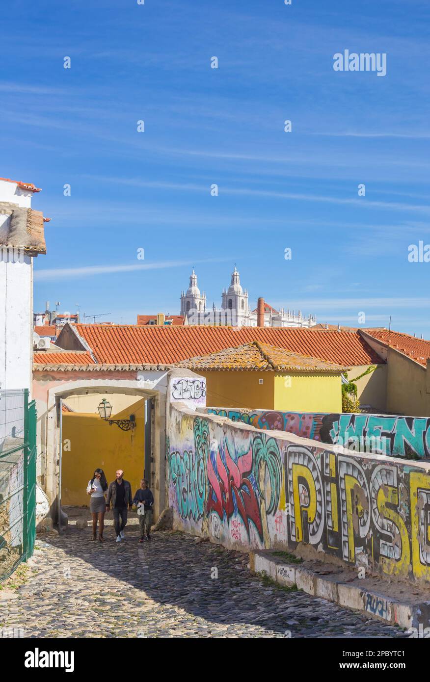 Old wall with graffiti at a cobblestoned street in Lisbon, Portugal Stock Photo