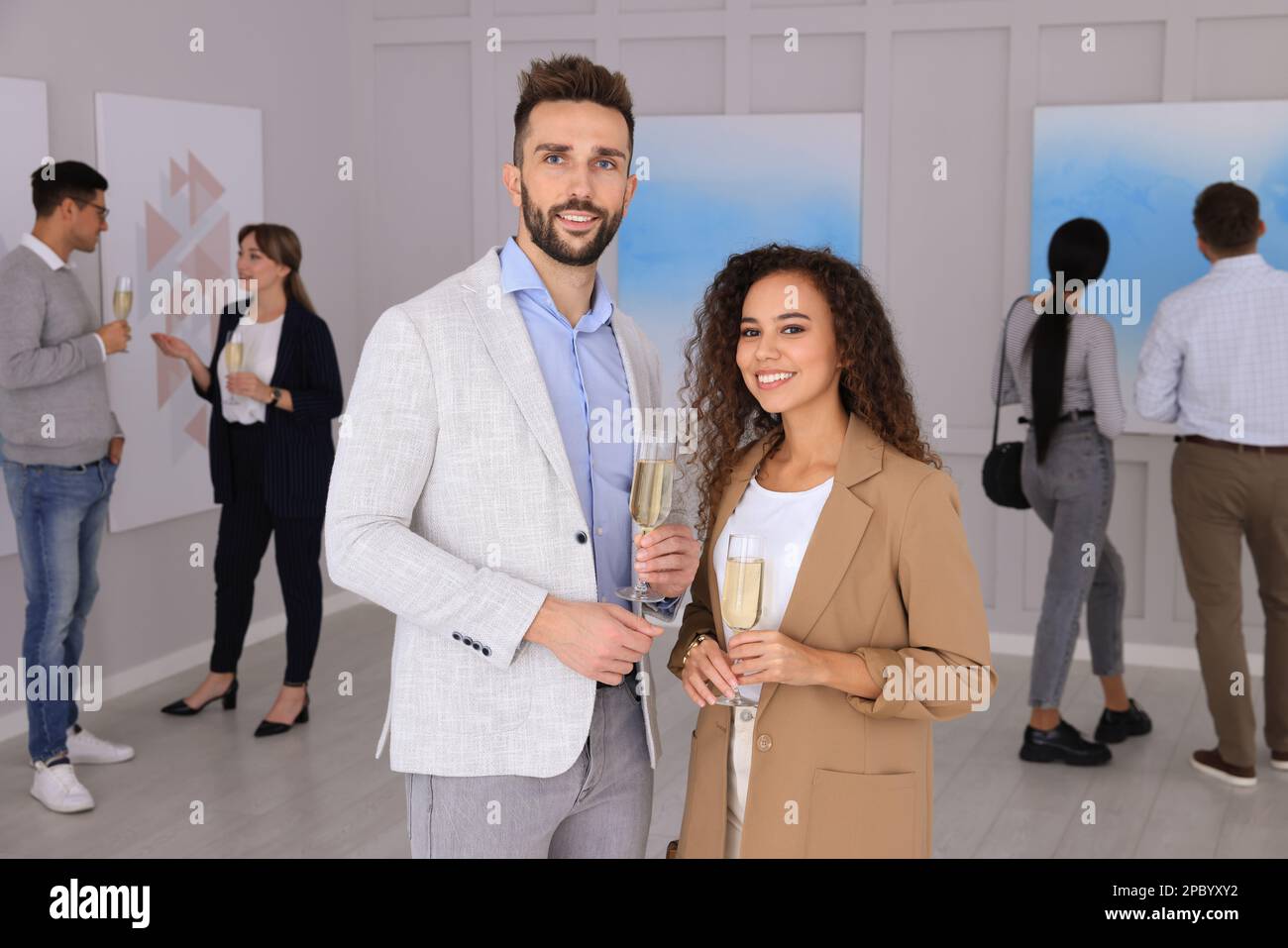 Couple with glasses of champagne at exhibition in art gallery Stock Photo