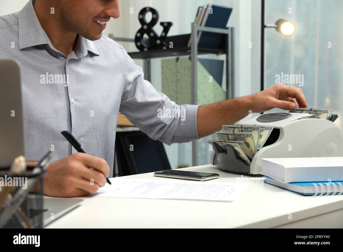 Man using banknote counter at white table indoors, closeup Stock Photo ...