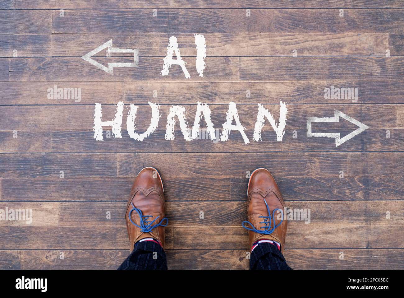 Man looking down at the words Artificial Intelligence - AI - and Human chalked onto the floor Stock Photo