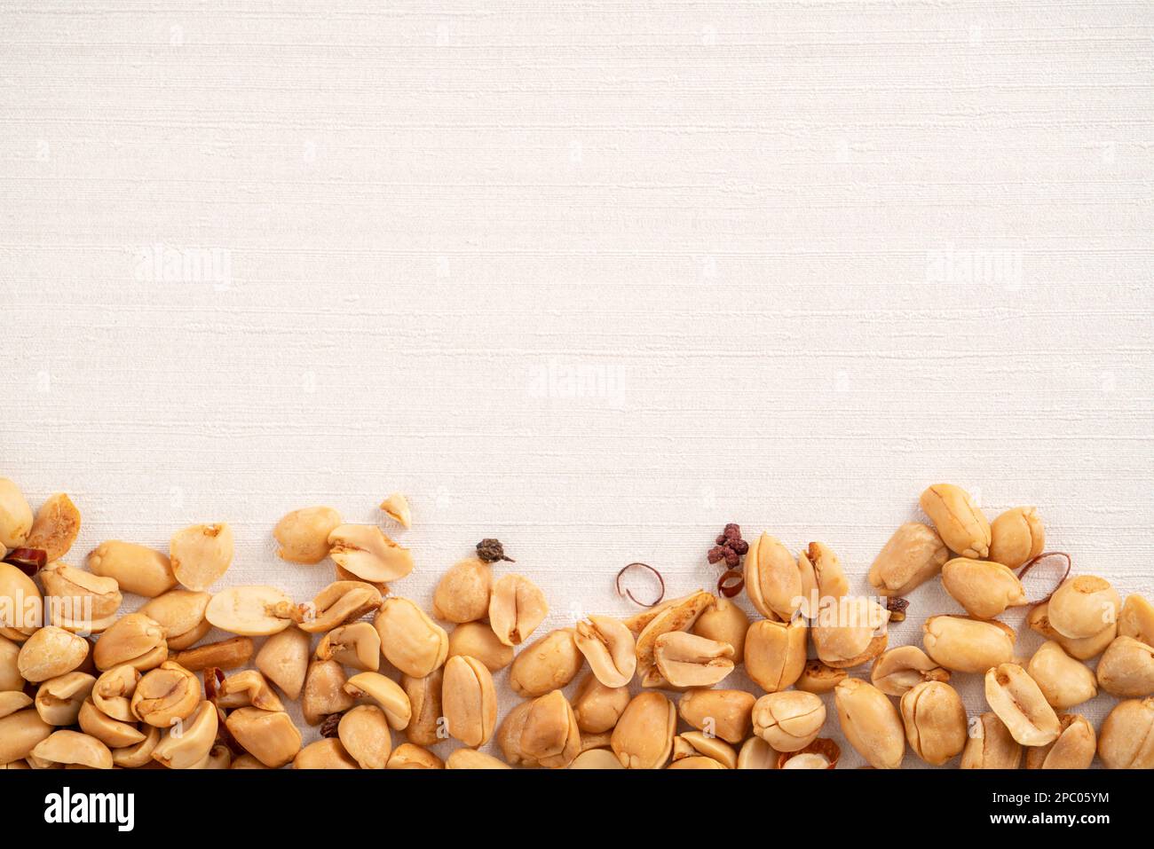 Spicy flavored peanut kernel spilling on white table background. Stock Photo