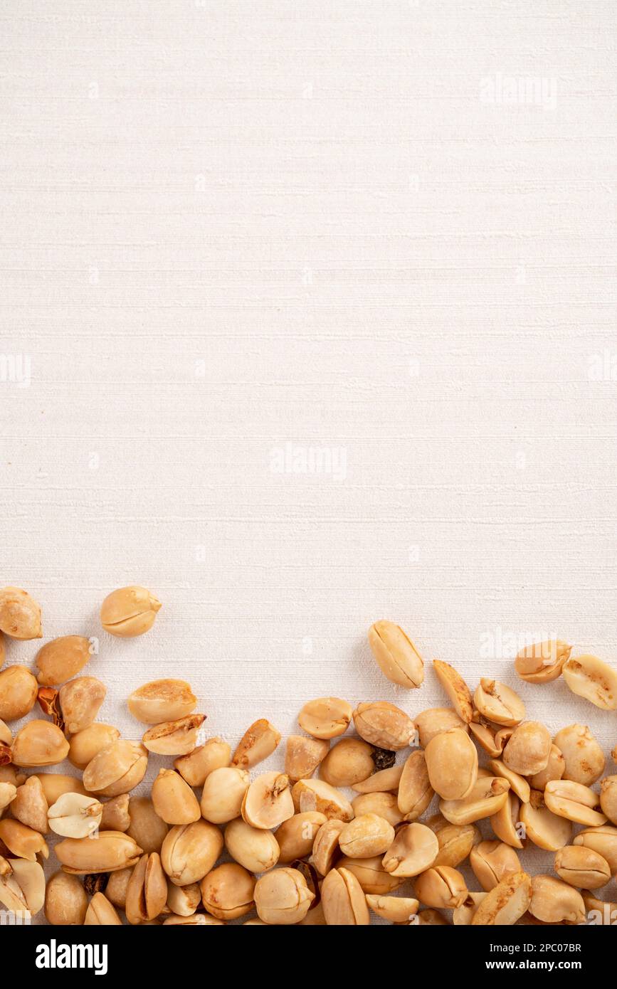 Spicy flavored peanut kernel spilling on white table background. Stock Photo