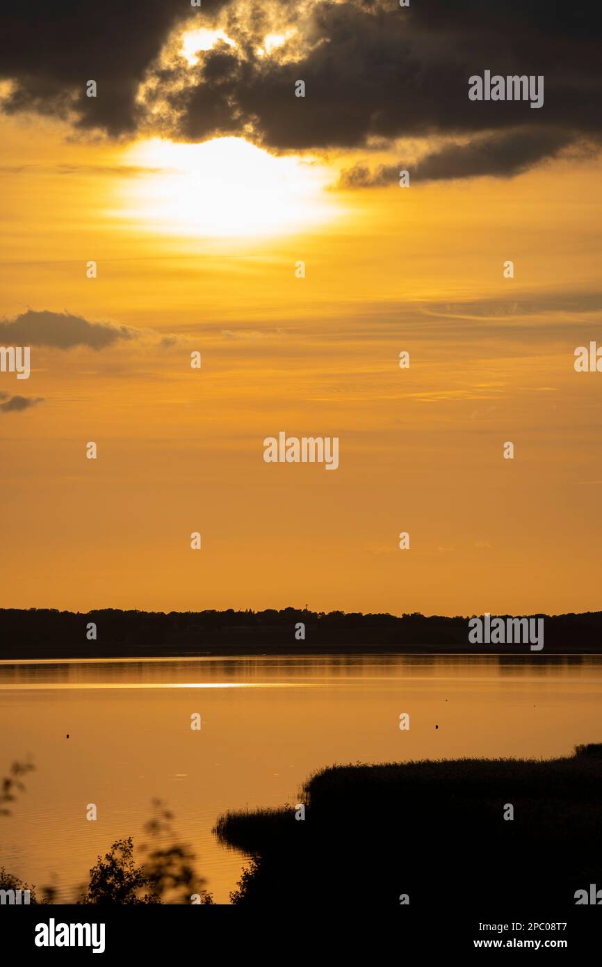 orange sunsed light on a lake with the sky full of clouds Stock Photo ...