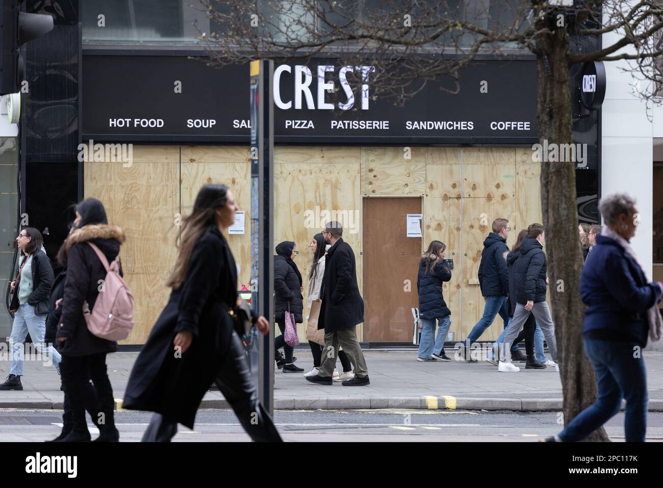 Shoppers walk past a boarded up shopfront on Oxford Street, as the retail sector struggles with high inflation and the fallout from Brexit and Covid. Stock Photo