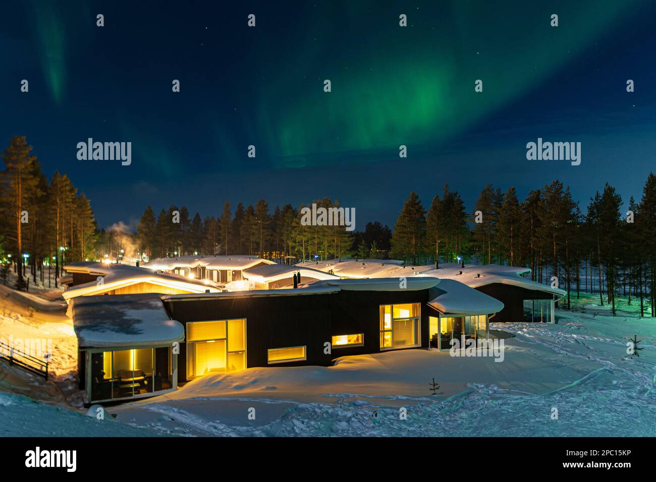 Aurora Over Huts In Winter In Kuusamo, Finland. Stock Photo
