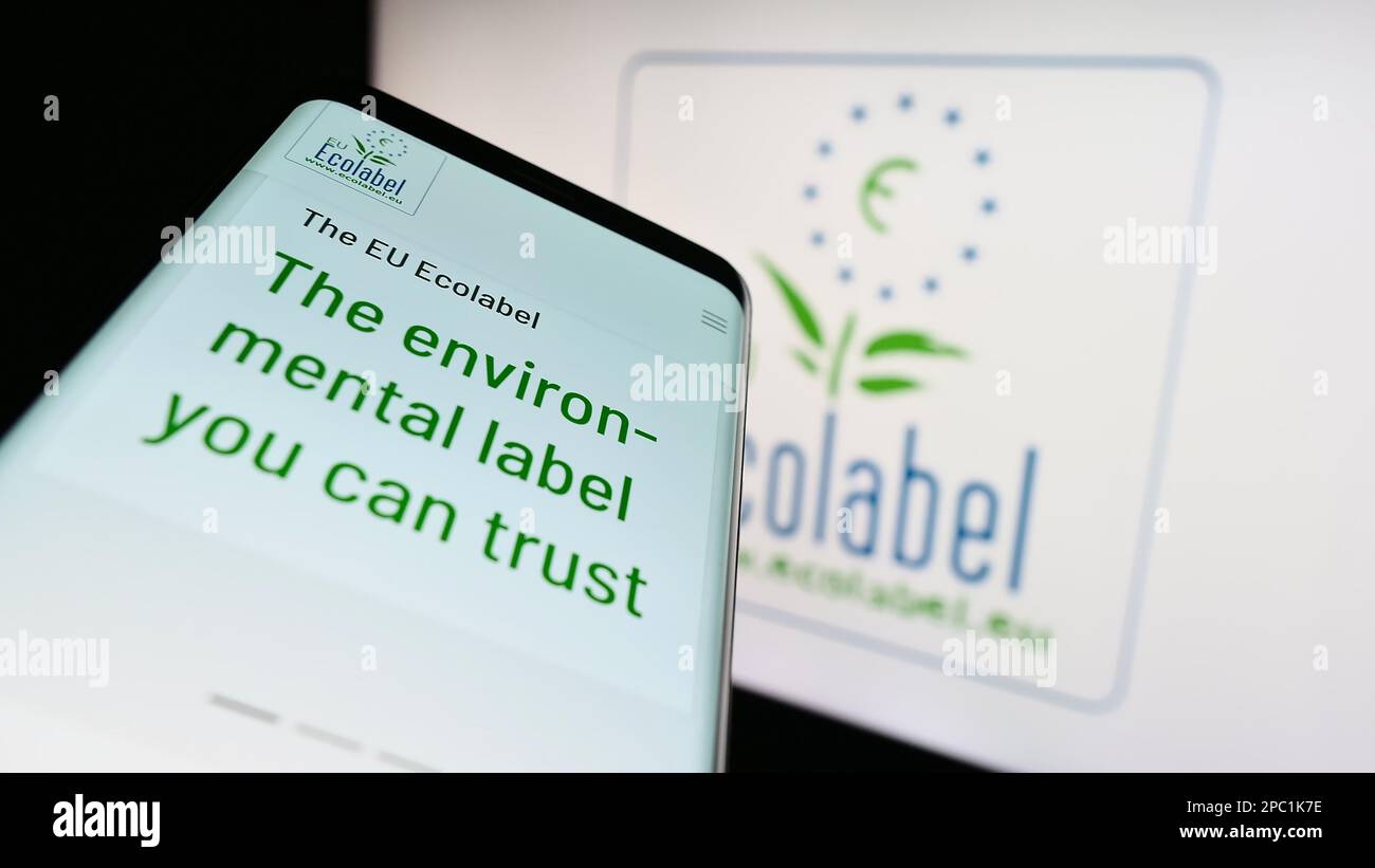Mobile phone with webpage of environmental certification EU Ecolabel on screen in front of logo. Focus on top-left of phone display. Stock Photo