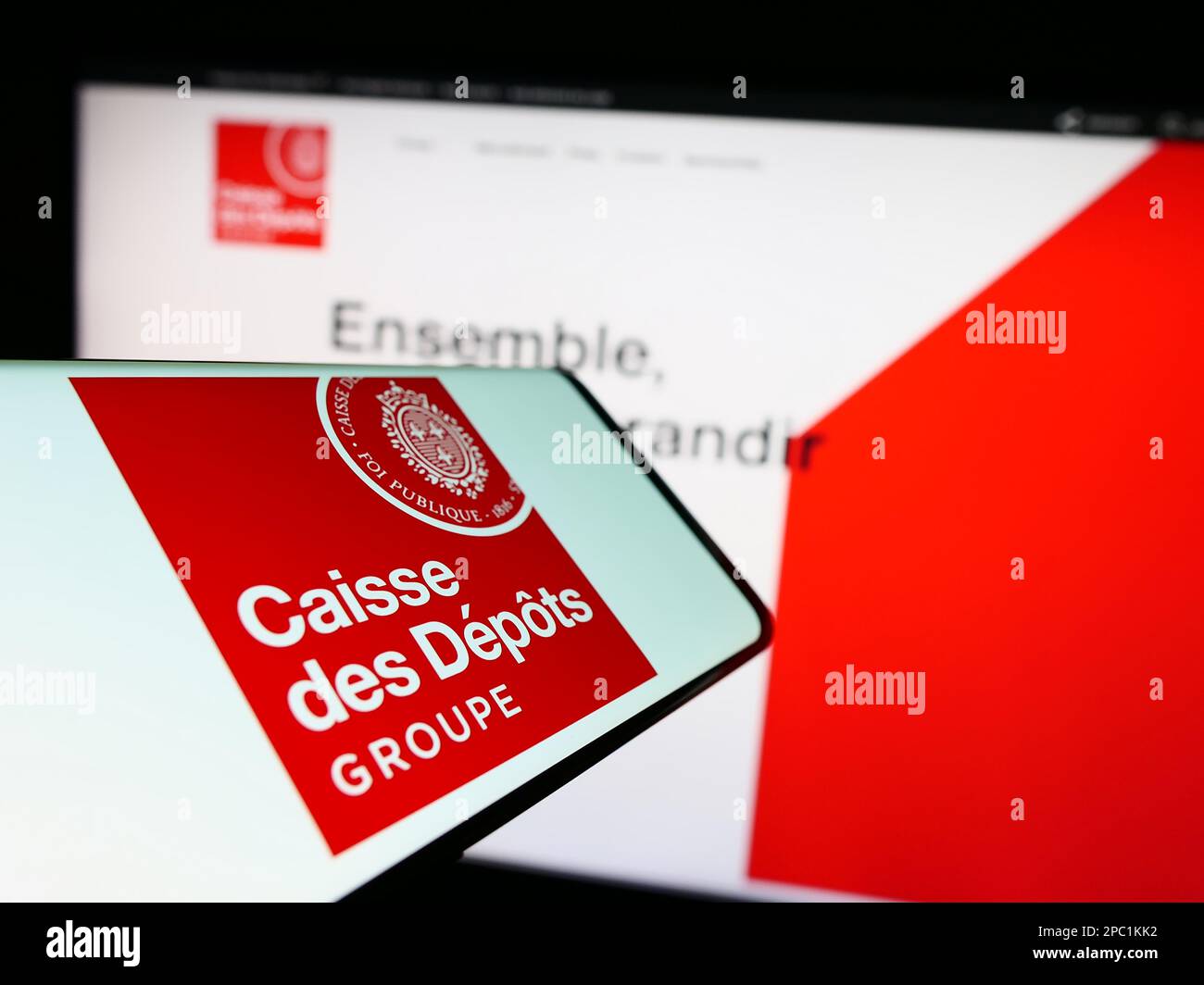 Cellphone with logo of Caisse des Depots et Consignations (CDC) on screen in front of website. Focus on right of phone display. Stock Photo