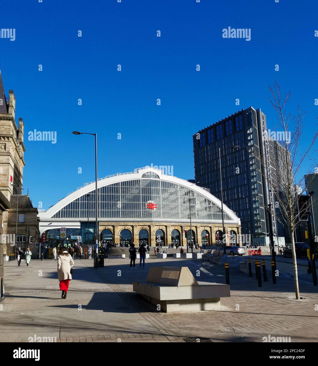 10th March 2023 - Liverpool Lime STreet station with a woman in red in the foreground echoing the colour of the station logo. Stock Photo