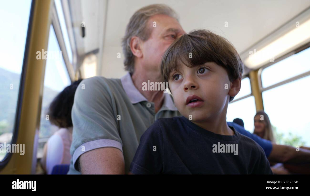Grandfather traveling by train with grandchild seated by window looking ...