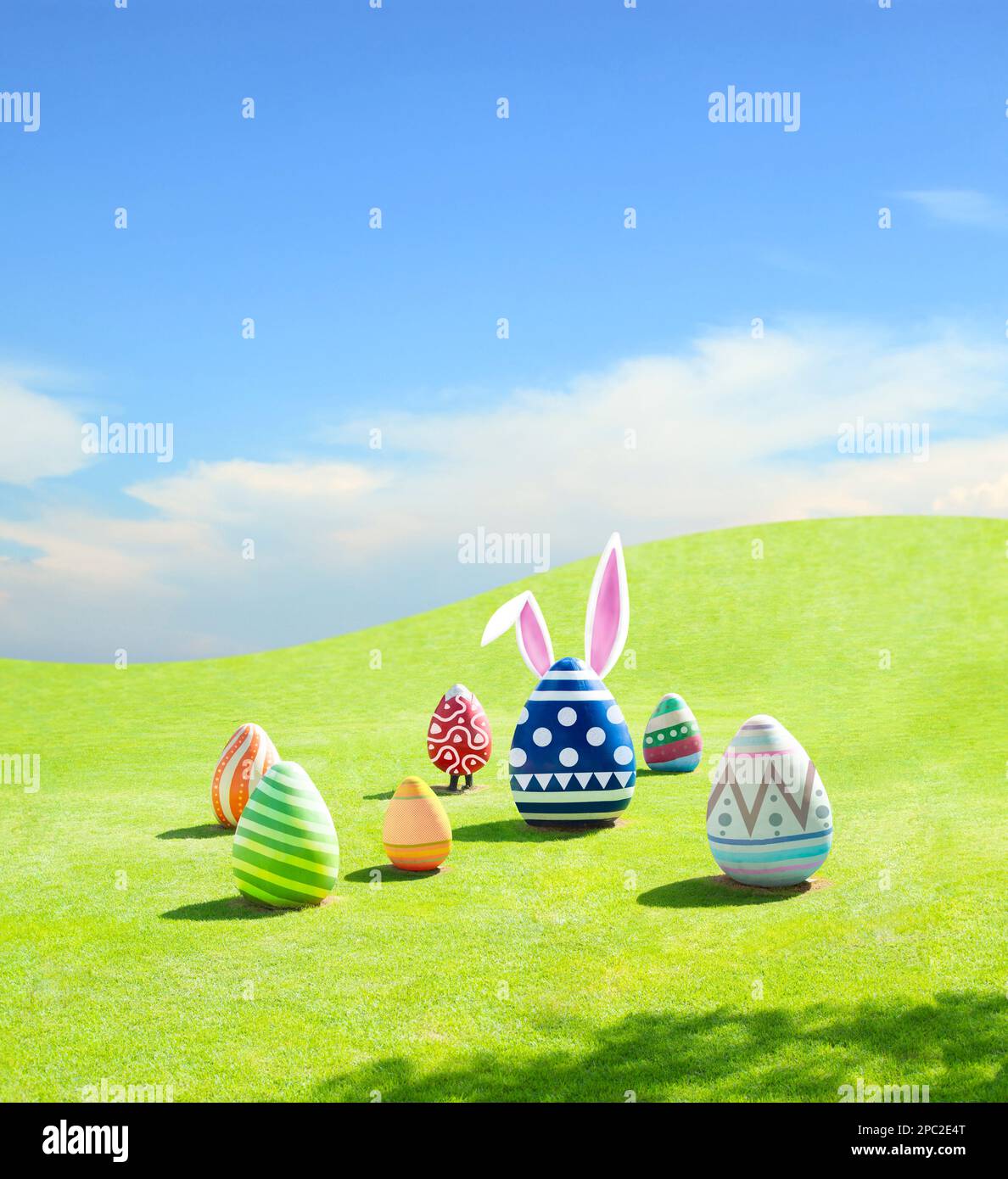 Easter eggs with bunny ears on green grass mountain and blue sky ...