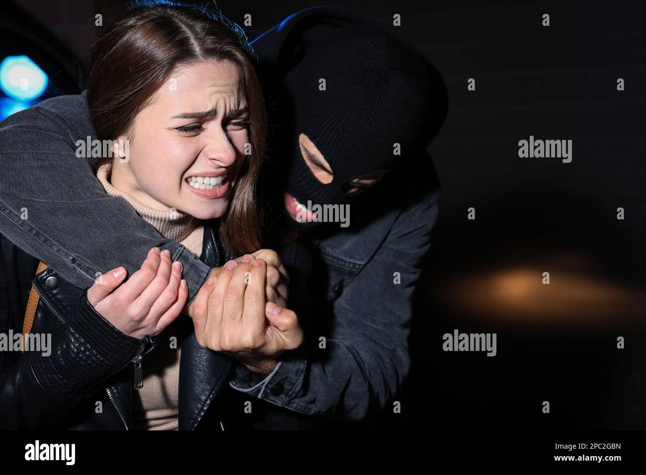 Woman defending herself from attacker outdoors at night Stock Photo