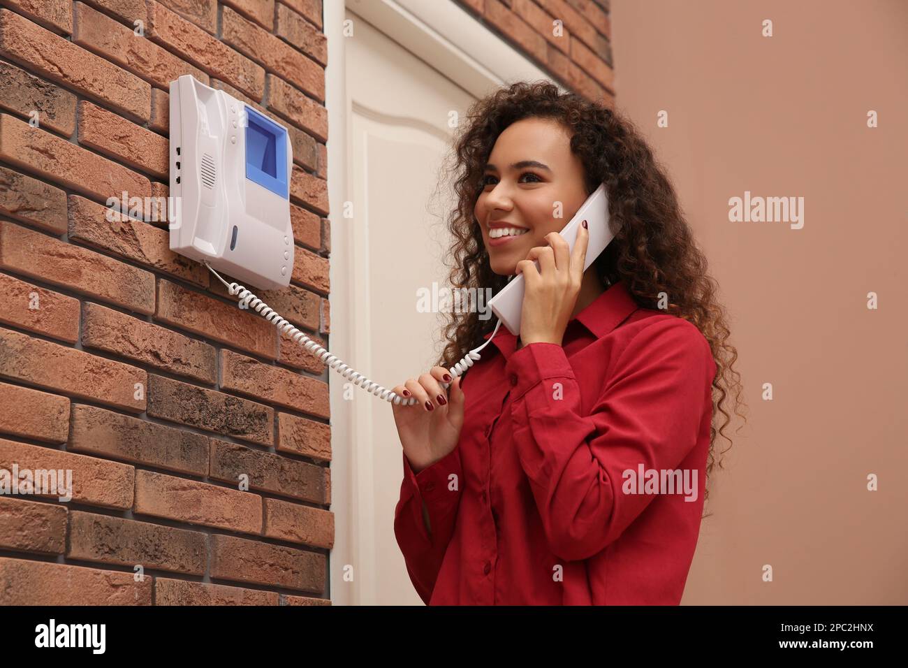 Young African-American woman answering intercom call indoors Stock ...