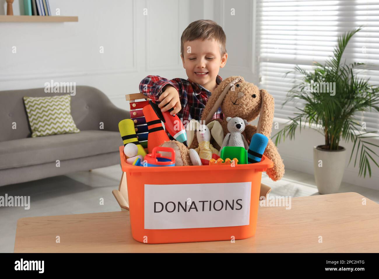 Cute little boy putting toy into donation box at home Stock Photo Alamy