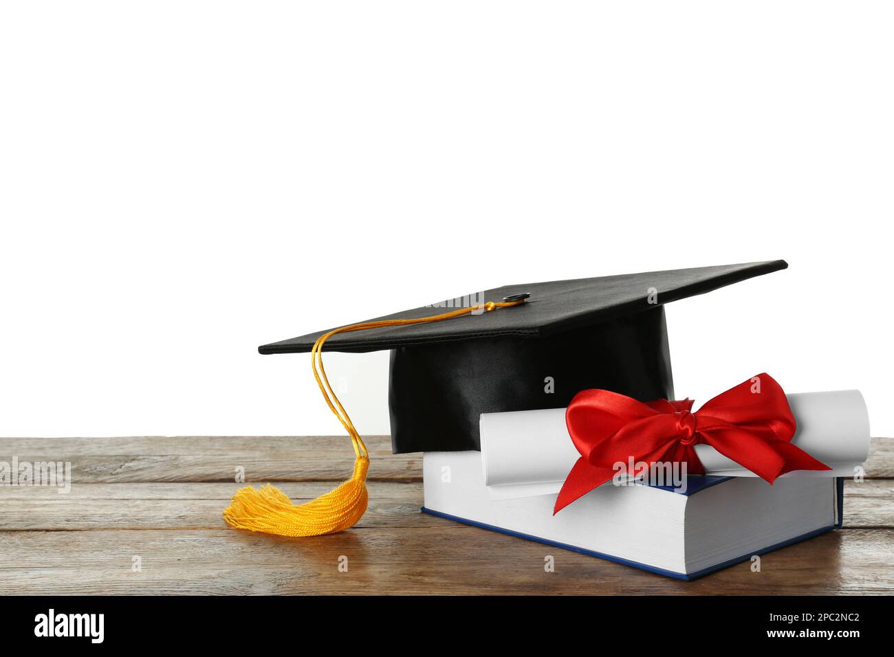 Graduation hat, book and diploma on wooden table against white ...