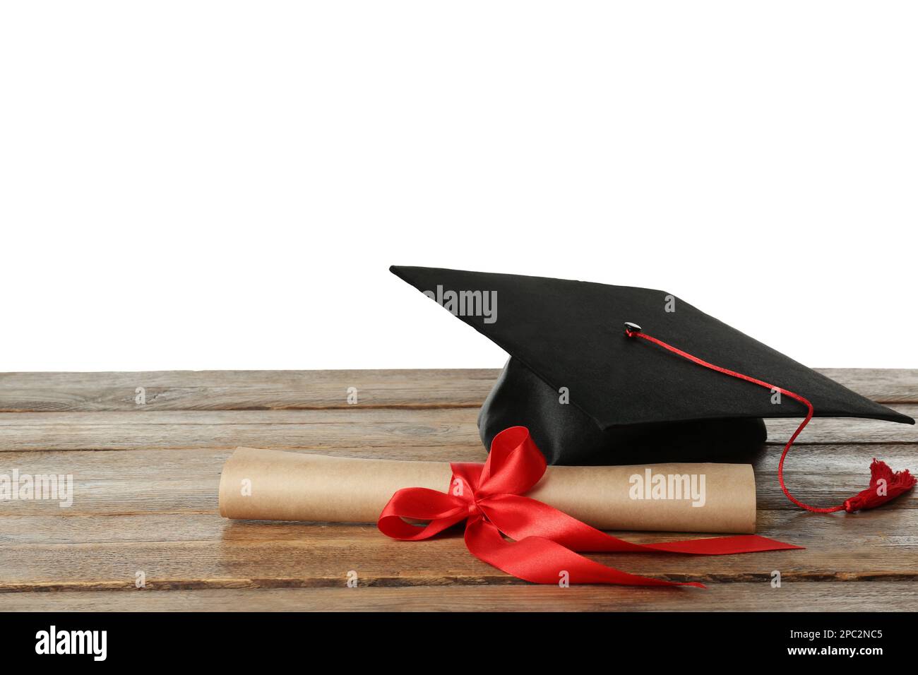 Graduation hat and diploma on wooden table against white background ...