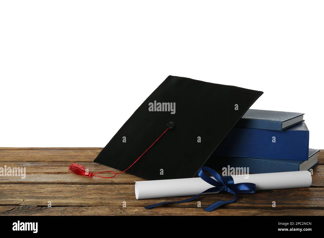 Graduation hat, books and diploma on wooden table against white ...