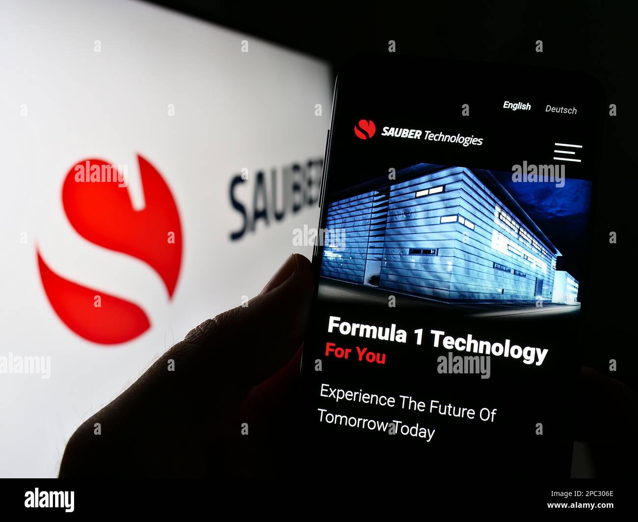 Person holding cellphone with webpage of Swiss automotive company Sauber Motorsport AG on screen with logo. Focus on center of phone display. Stock Photo
