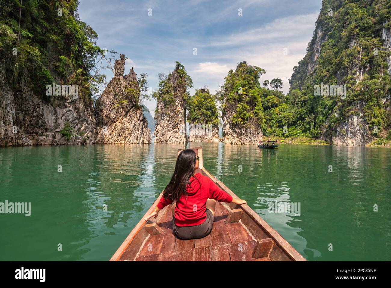 Boat riding through mountain lake view with woman tourist and tropical forest at Sam Klur mountain Khaosok National Park, Surat Thani Thailand nature Stock Photo