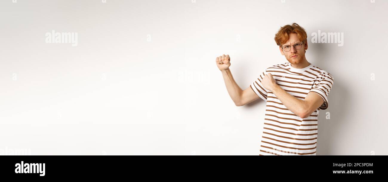 Serious and confident redhead man in glasses raising fists, ready for ...