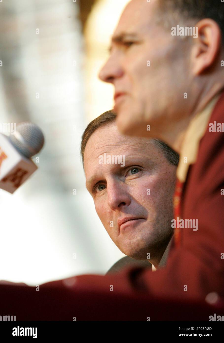 New Minnesota football coach Tim Brewster, left, listens to comments