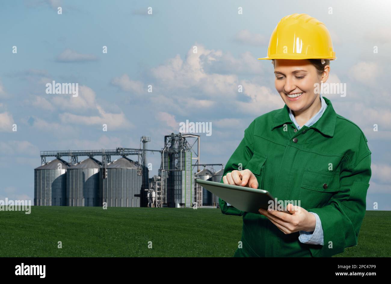 Woman engineer with a digital tablet on a background of agricultural silos for biofuel production Stock Photo