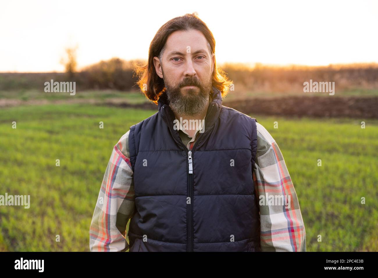 Portrait of bearded farmer on a field at sunset. Stock Photo