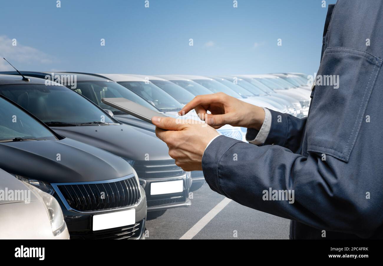 Hands with digital tablet on a background of rows of cars. Car sales. Stock Photo