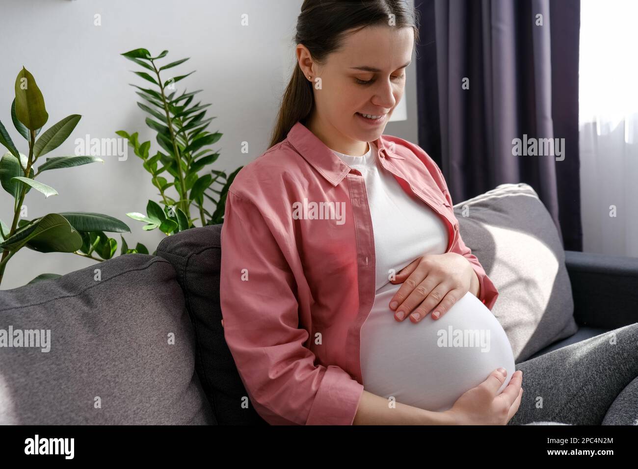 Happy maternity concept. Smiling young single pregnant woman sitting on