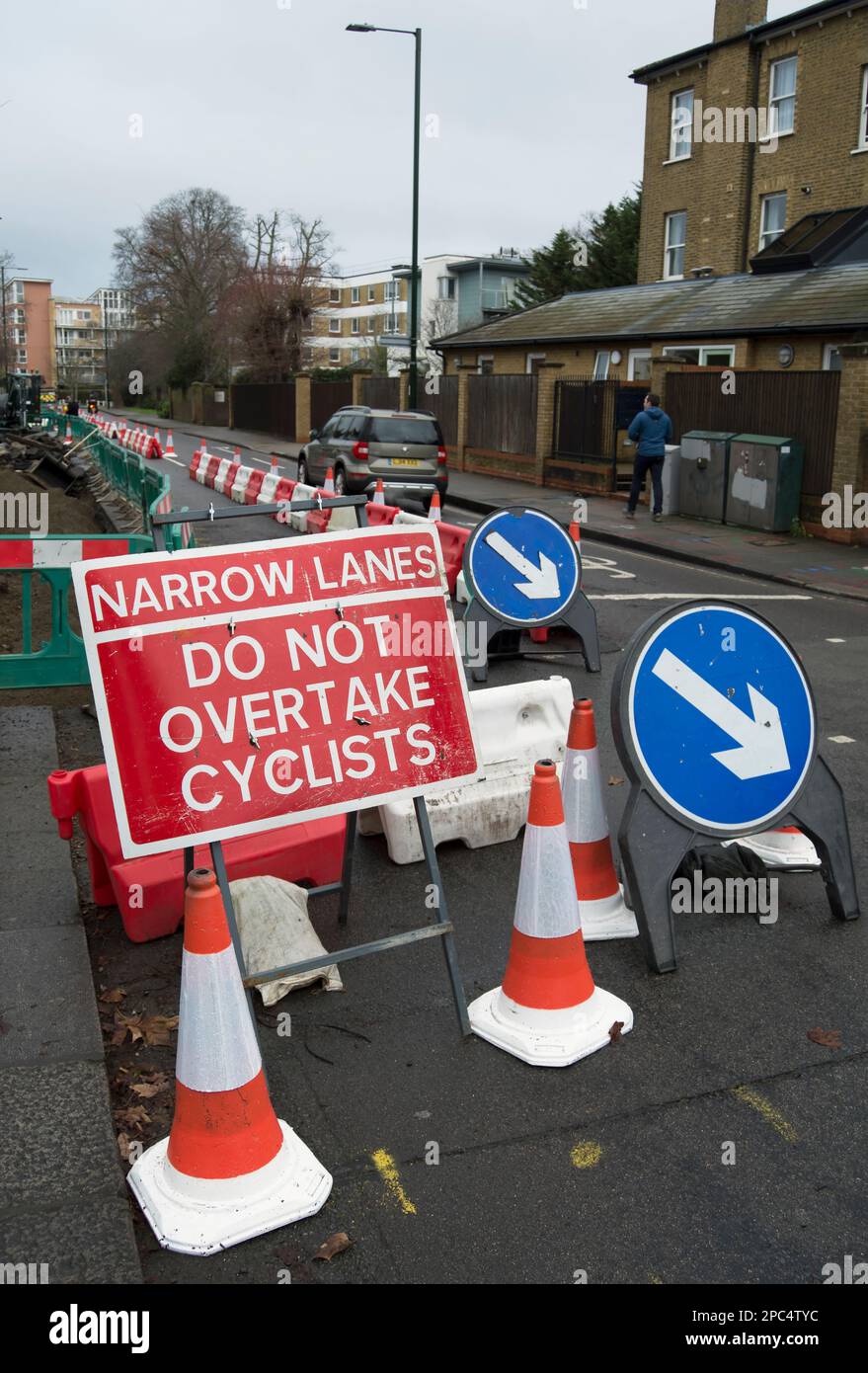narrow lane do not overtake cyclists sign at road works in teddington, middlesex, england, beside cones and direction signs Stock Photo