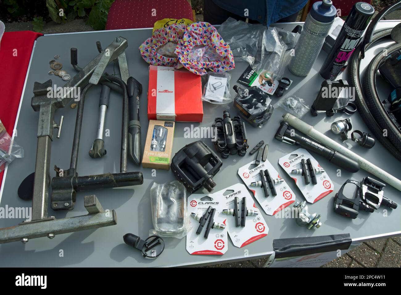 assorted cycle parts and cycle accessories on a table having been donated for sale at the 2023 kew ecofair, london, england Stock Photo