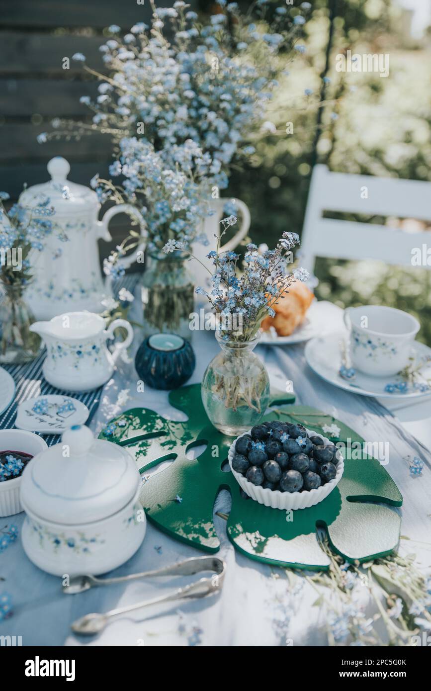 The aesthetic table set with white tea cups with blue flowers in nature