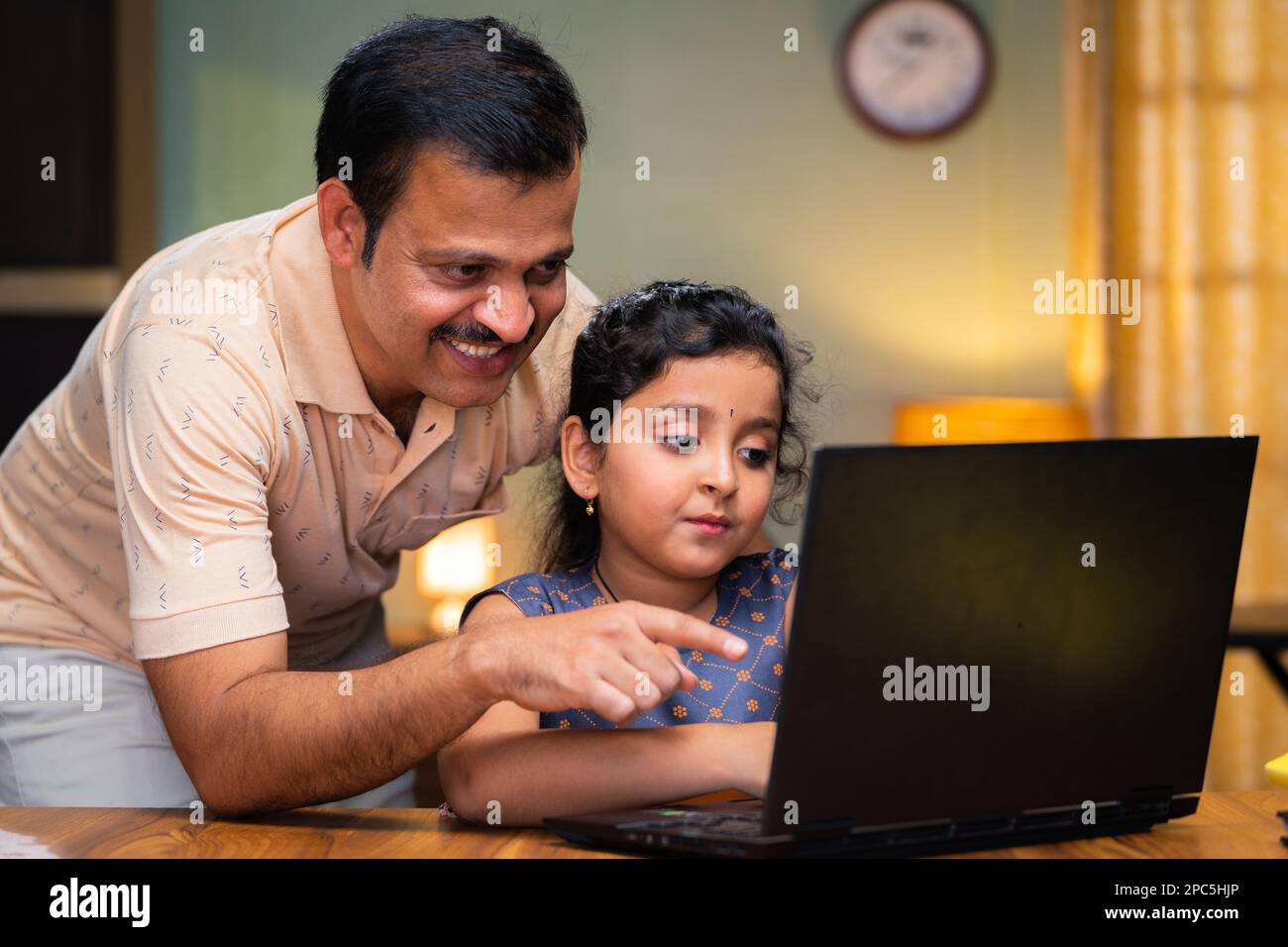 Father teaching or explaining from laptop to kid at home - concept of home schooling, caring and childhood growth or development. Stock Photo